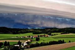 Eine Gewitterfront mit Sturm und Starkregen rollt in hoher Geschwindigkeit heran. Hier über der Ortschaft Holzham und aus der Sicht in Holzham